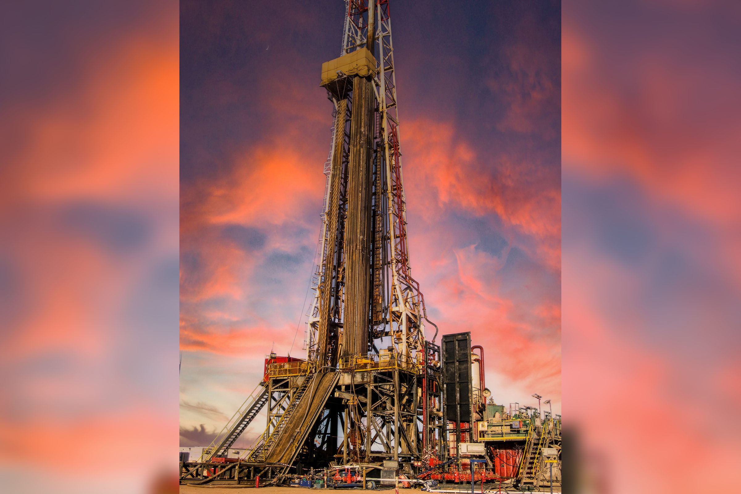 Oil drilling rig set against a vibrant sunset sky.