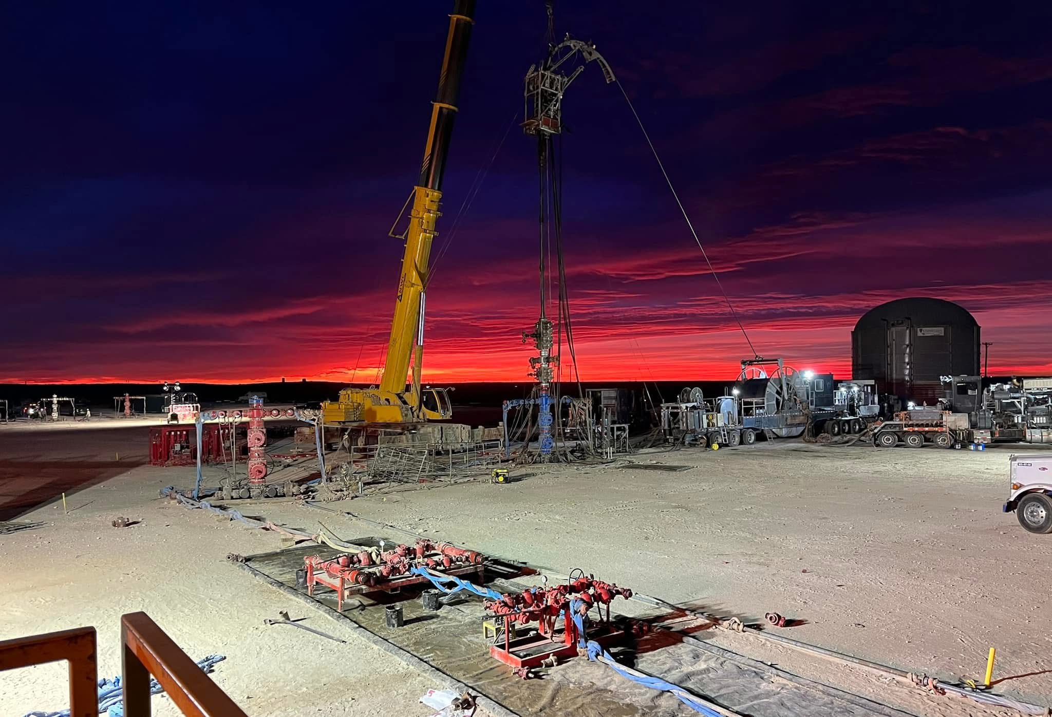 Construction site at sunset with a crane lifting materials.