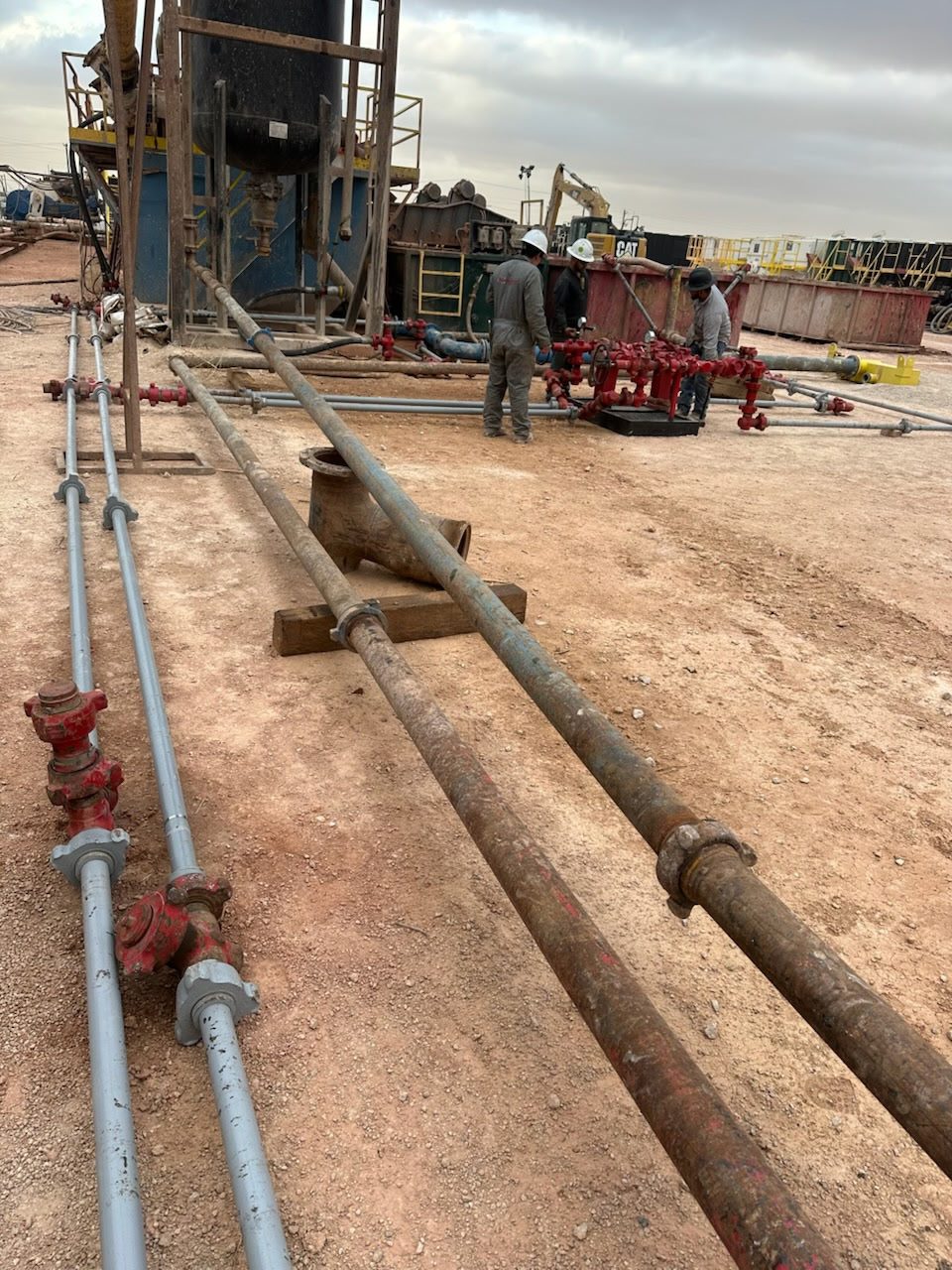 Worker in safety gear at a construction site with machinery and materials.