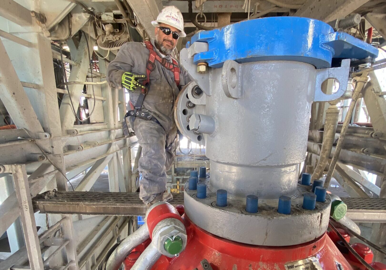 Worker inspecting heavy industrial valve in a factory setting.